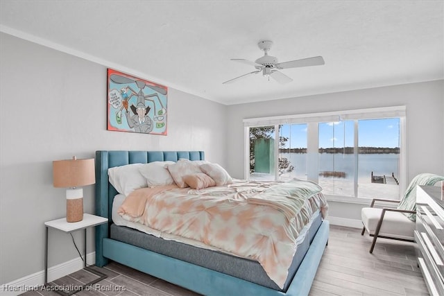 bedroom featuring hardwood / wood-style flooring, ceiling fan, and a water view