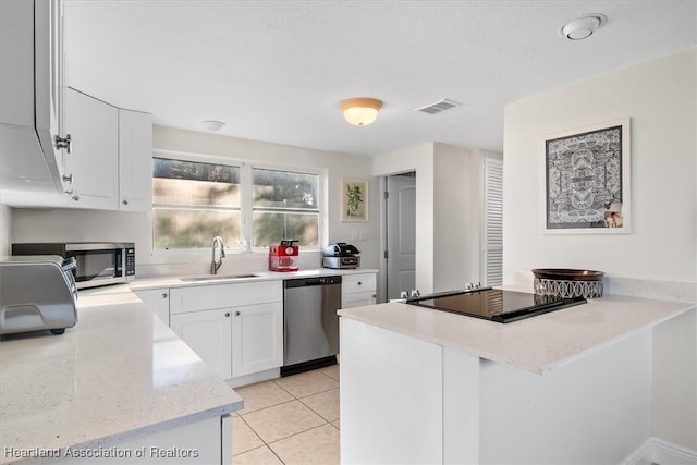 kitchen with white cabinetry, sink, light tile patterned floors, stainless steel appliances, and light stone countertops