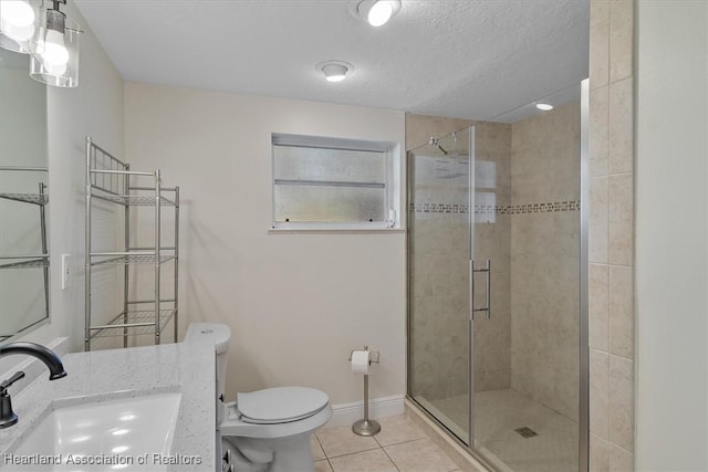 bathroom featuring tile patterned flooring, vanity, toilet, a shower with door, and a textured ceiling