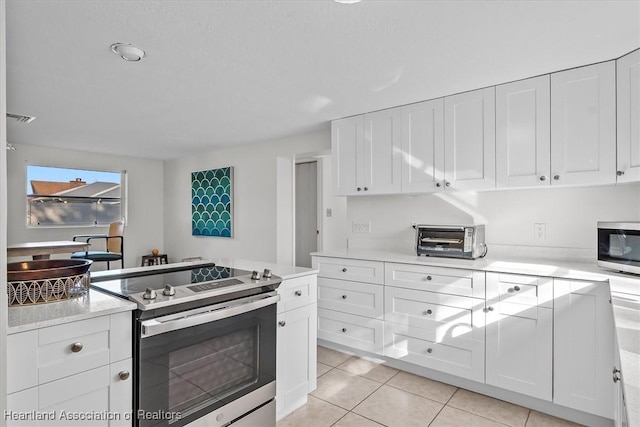 kitchen featuring light tile patterned floors, white cabinets, and appliances with stainless steel finishes