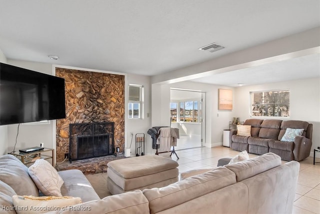 tiled living room with a stone fireplace