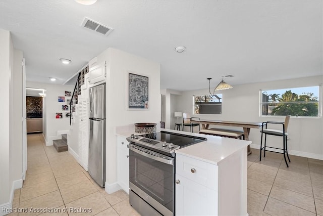 kitchen with light tile patterned flooring, stainless steel appliances, decorative light fixtures, and white cabinets