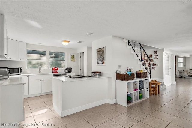 kitchen with white cabinetry, light tile patterned floors, sink, and a textured ceiling