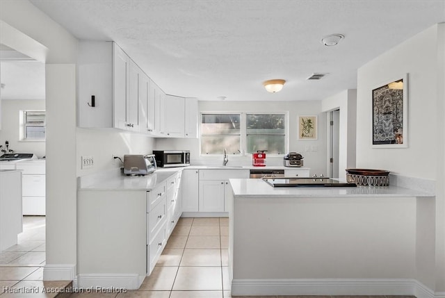 kitchen featuring white cabinetry, stainless steel appliances, washing machine and clothes dryer, and light tile patterned flooring