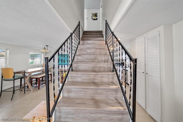 staircase with tile patterned floors and a textured ceiling