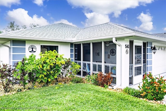 rear view of property with a garage and a lawn