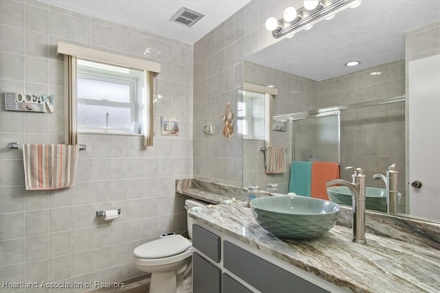 bathroom featuring vanity, toilet, an enclosed shower, and tile walls