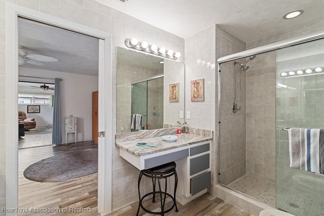 bathroom featuring tile walls, ceiling fan, hardwood / wood-style floors, and an enclosed shower