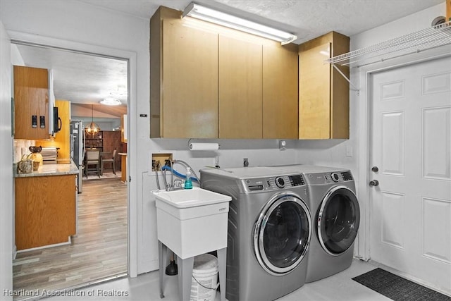 laundry room featuring washer and clothes dryer, cabinets, and a textured ceiling