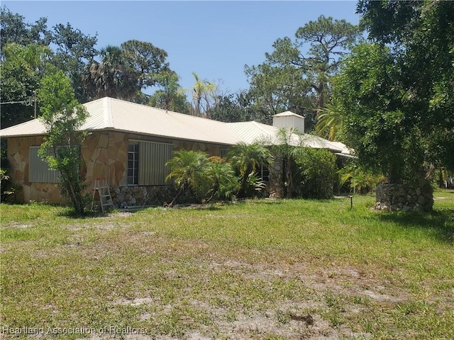 12115 S US Highway 41, Gibsonton, FL 33534 - view of side of property with stone siding, a metal roof, and a yard