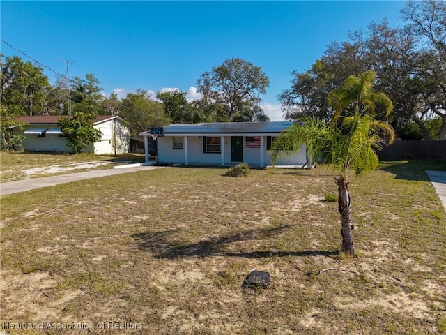 view of front facade with solar panels, driveway, fence, and a front yard
