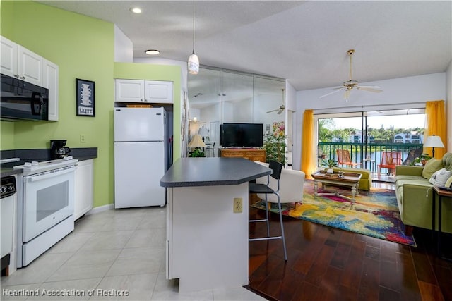 kitchen featuring ceiling fan, a textured ceiling, white appliances, a breakfast bar, and white cabinets