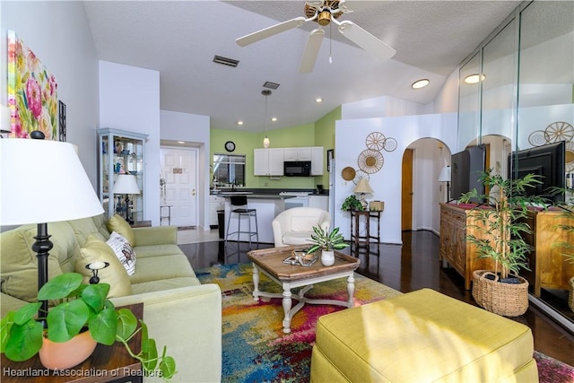 living room featuring a textured ceiling, dark hardwood / wood-style floors, high vaulted ceiling, and ceiling fan