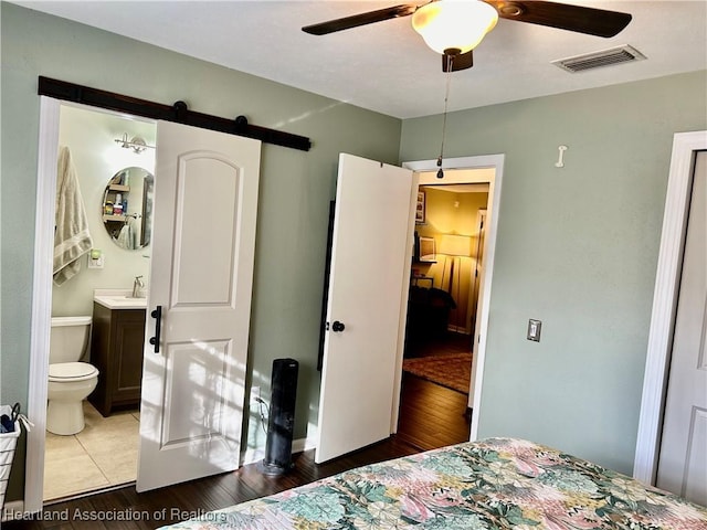 bedroom featuring sink, connected bathroom, ceiling fan, and a barn door