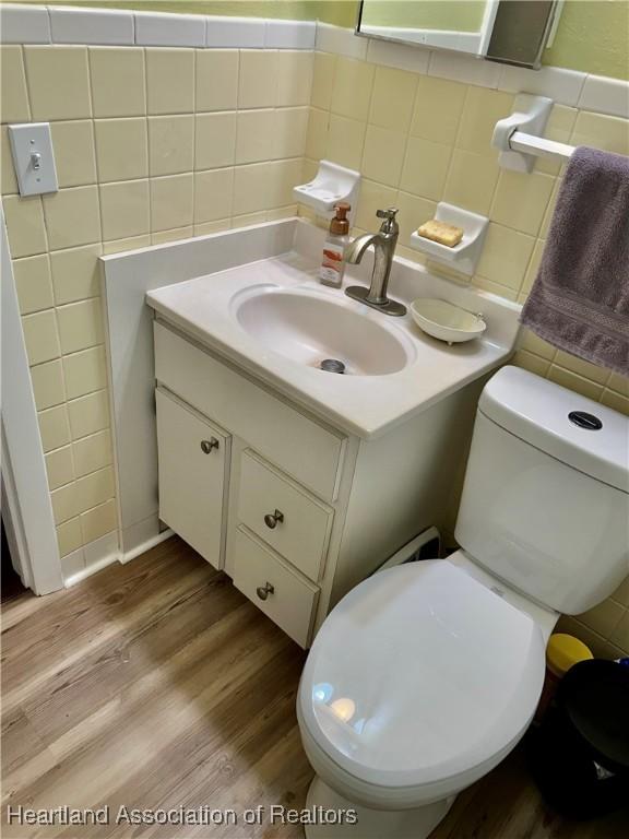 bathroom with toilet, vanity, tile walls, and hardwood / wood-style floors