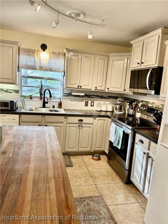 kitchen featuring sink, stainless steel appliances, white cabinetry, and light tile patterned floors