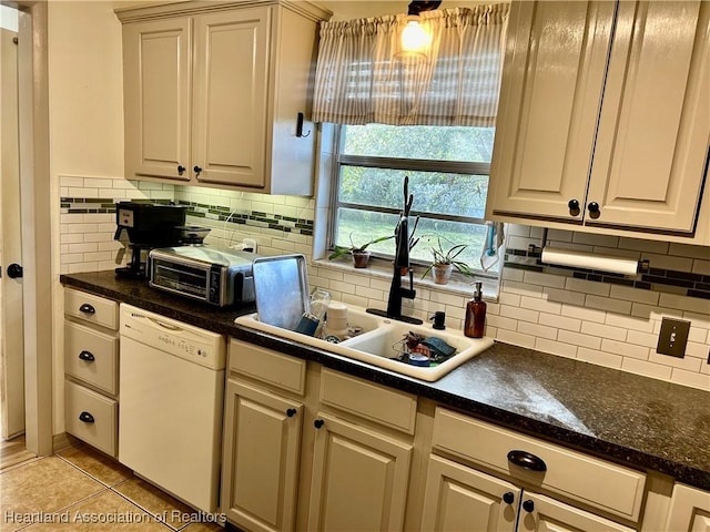 kitchen with white dishwasher, light tile patterned floors, backsplash, and sink