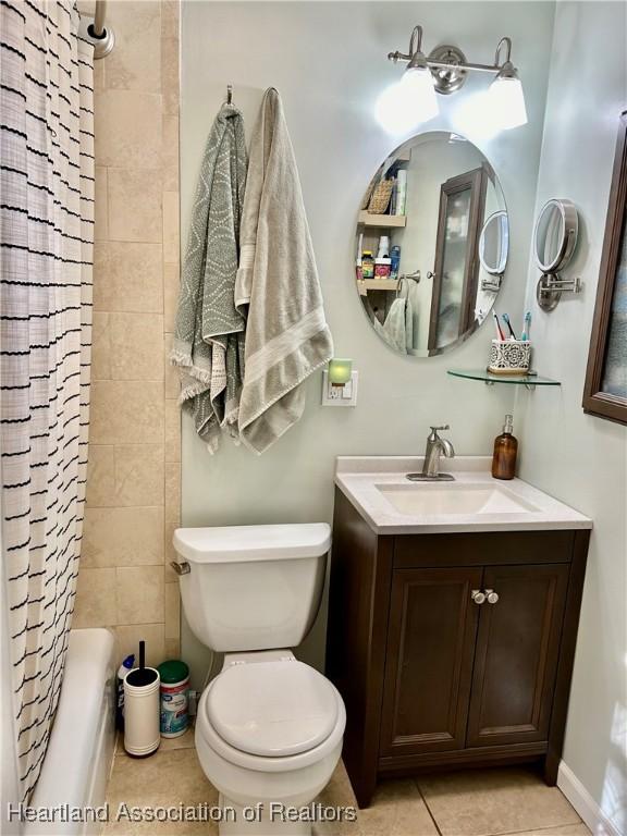 full bathroom featuring tile patterned flooring, shower / bath combo with shower curtain, vanity, and toilet