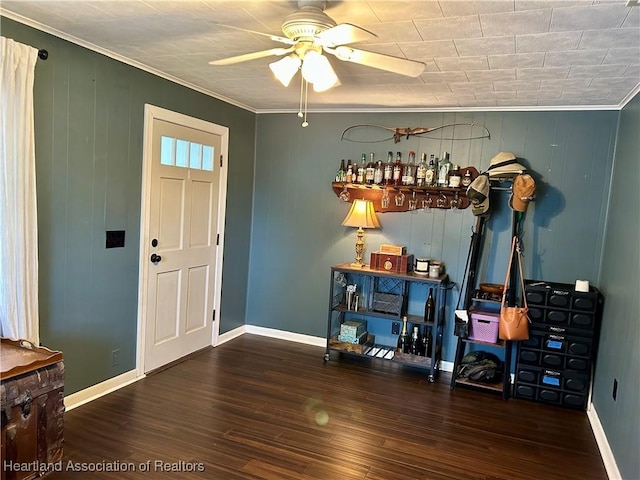 foyer featuring dark wood-type flooring, ceiling fan, ornamental molding, and bar area