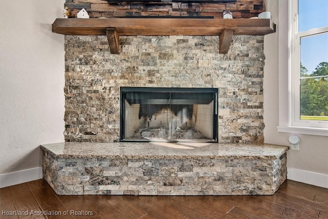 room details with a stone fireplace and wood-type flooring