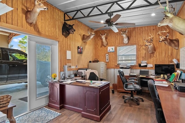 office area with ceiling fan, a healthy amount of sunlight, light hardwood / wood-style floors, and wood walls