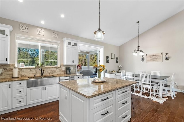 kitchen featuring white cabinetry, a kitchen island, sink, and hanging light fixtures