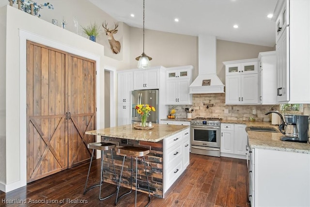 kitchen with stainless steel appliances, a kitchen island, custom range hood, and white cabinets