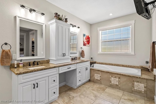 bathroom with vanity and tiled tub