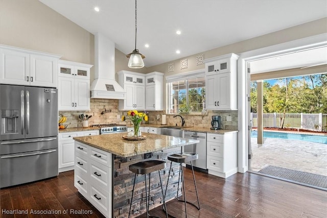 kitchen featuring premium range hood, a kitchen bar, white cabinetry, a kitchen island, and stainless steel appliances