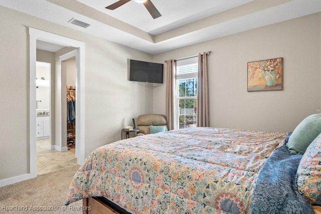 carpeted bedroom featuring ceiling fan and a tray ceiling