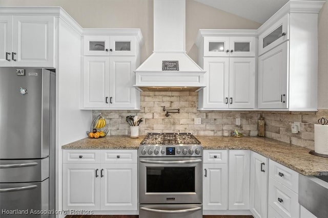 kitchen featuring backsplash, custom range hood, white cabinets, and appliances with stainless steel finishes