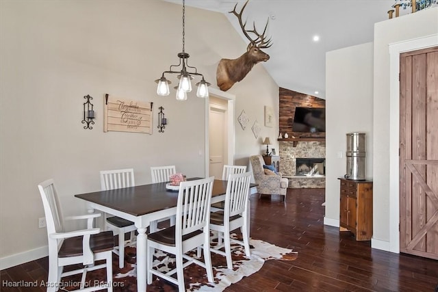 dining space featuring lofted ceiling, a notable chandelier, a stone fireplace, and dark wood-type flooring