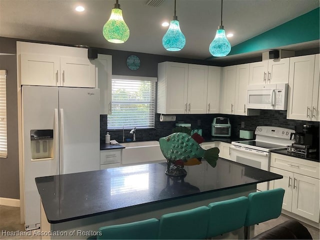 kitchen featuring lofted ceiling, white cabinets, hanging light fixtures, and white appliances