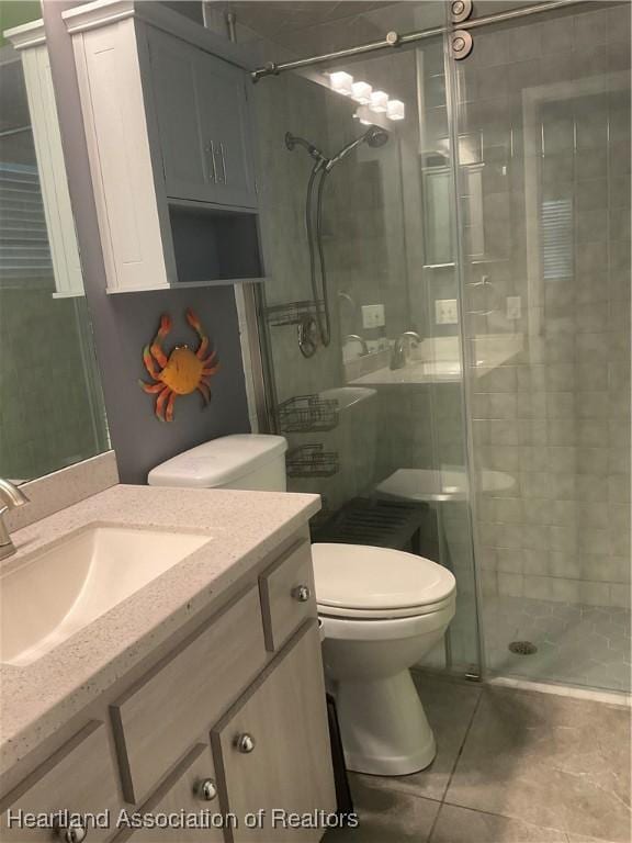 bathroom with toilet, vanity, tile patterned floors, and a shower with door