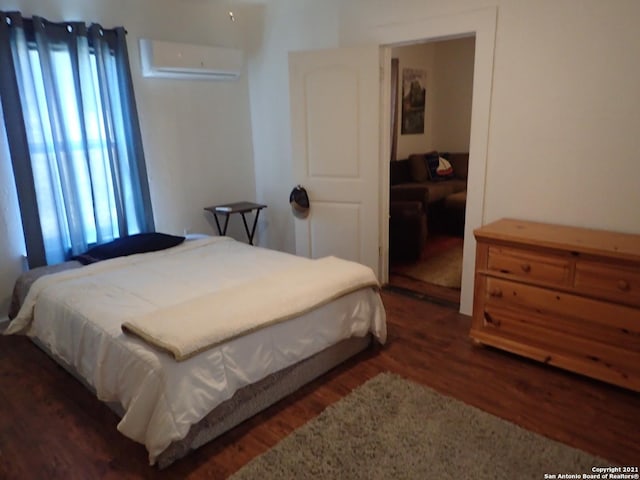 bedroom featuring dark hardwood / wood-style flooring and a wall unit AC