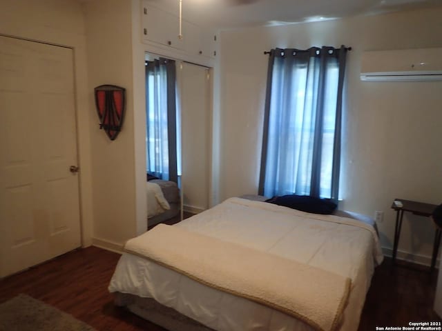 bedroom featuring an AC wall unit, multiple windows, a closet, and dark wood-type flooring