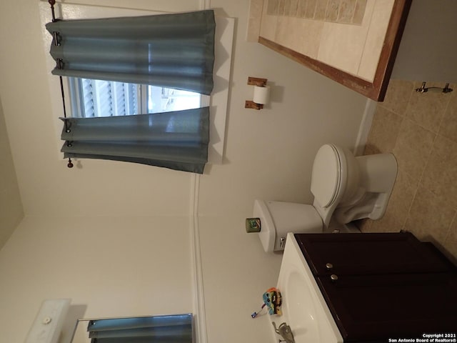 bathroom with tile walls, toilet, and vanity