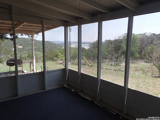 unfurnished sunroom featuring beam ceiling and a wealth of natural light