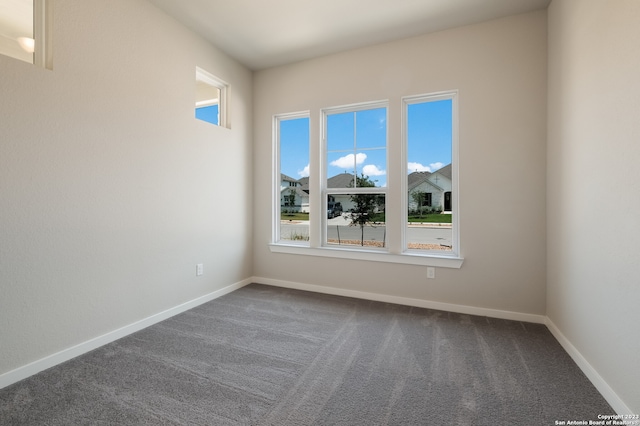 unfurnished room with dark carpet and a wealth of natural light