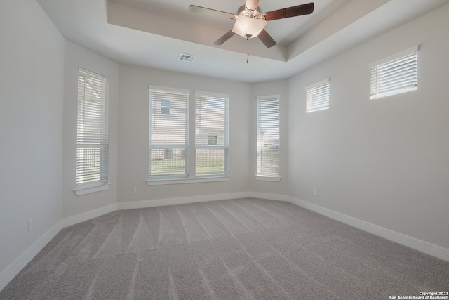 spare room featuring ceiling fan, a tray ceiling, and carpet flooring