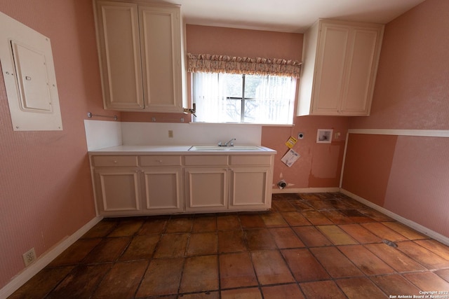 kitchen with dark tile flooring, white cabinets, and sink