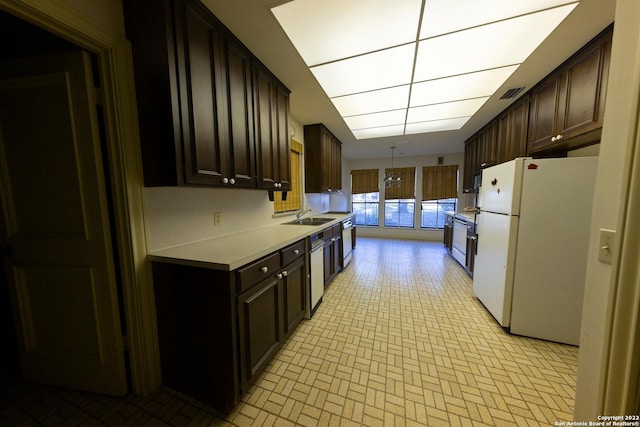 kitchen with dark brown cabinets, sink, and white refrigerator