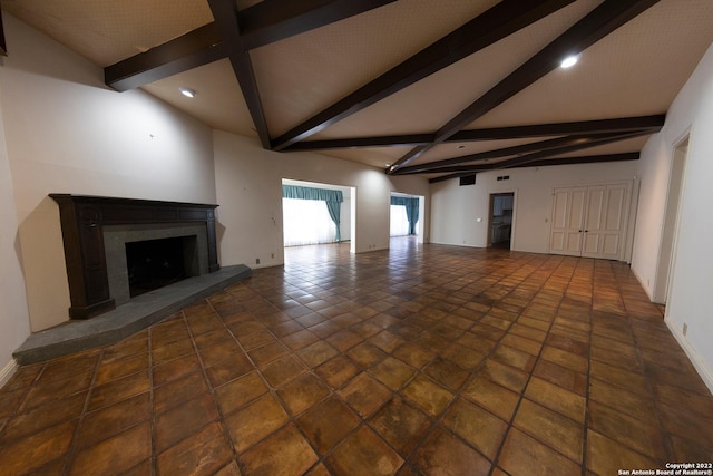 unfurnished living room featuring high vaulted ceiling, beam ceiling, and dark tile floors