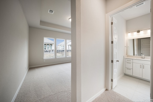 hall featuring light colored carpet and sink