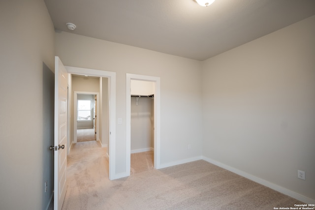 unfurnished bedroom featuring light colored carpet, a spacious closet, and a closet