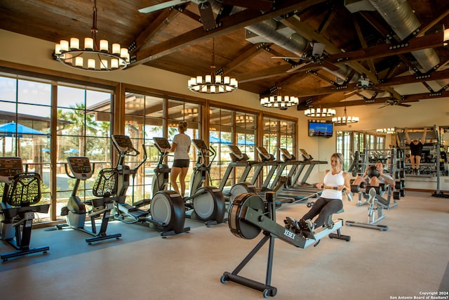 gym featuring a wealth of natural light and ceiling fan with notable chandelier