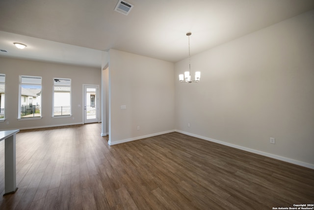 spare room with dark hardwood / wood-style floors and an inviting chandelier