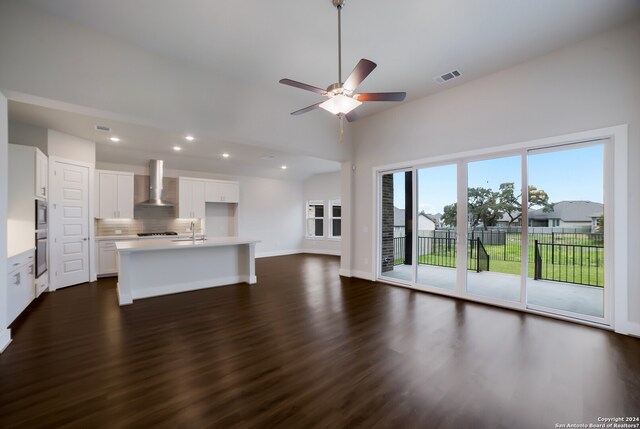 unfurnished living room with dark hardwood / wood-style floors, ceiling fan, sink, and a towering ceiling