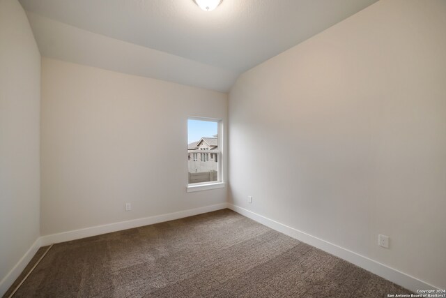 carpeted empty room with lofted ceiling