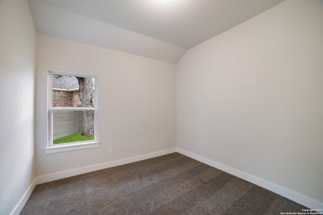 carpeted spare room featuring vaulted ceiling